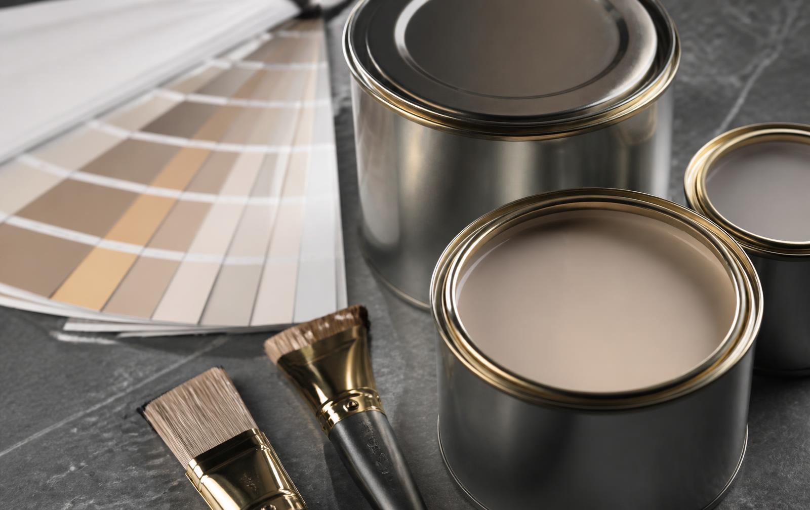 Premium paint tins, colour fan and fine brushes on dark stone